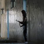 A Free Syrian Army fighter walks with his weapon inside a damaged building on the frontline of Aleppo’s Al-Ezaa neighbourhood